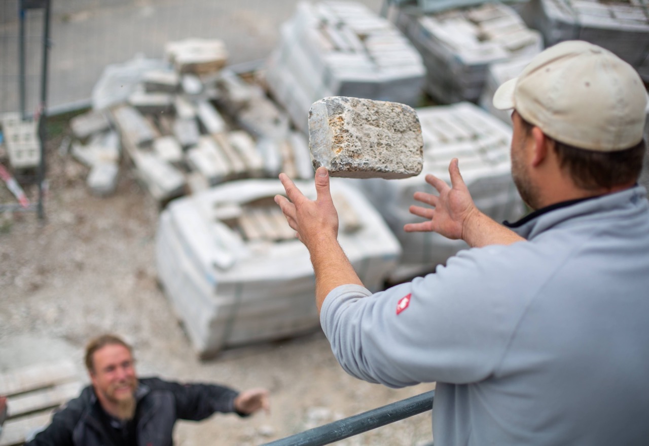 Arbeiter lässt Naturstein aus Kirchheimer Muschelkalk in seine Hände fallen